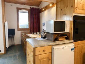 A compact kitchen with a microwave, toaster, and a small refrigerator.