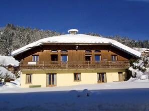 A wooden chalet with a balcony, surrounded by snow-covered trees. - Cozy Studio for 4 with Mezzanine, Wi-Fi, and Parking, 400m from Chavannes Gondola (Les Gets)