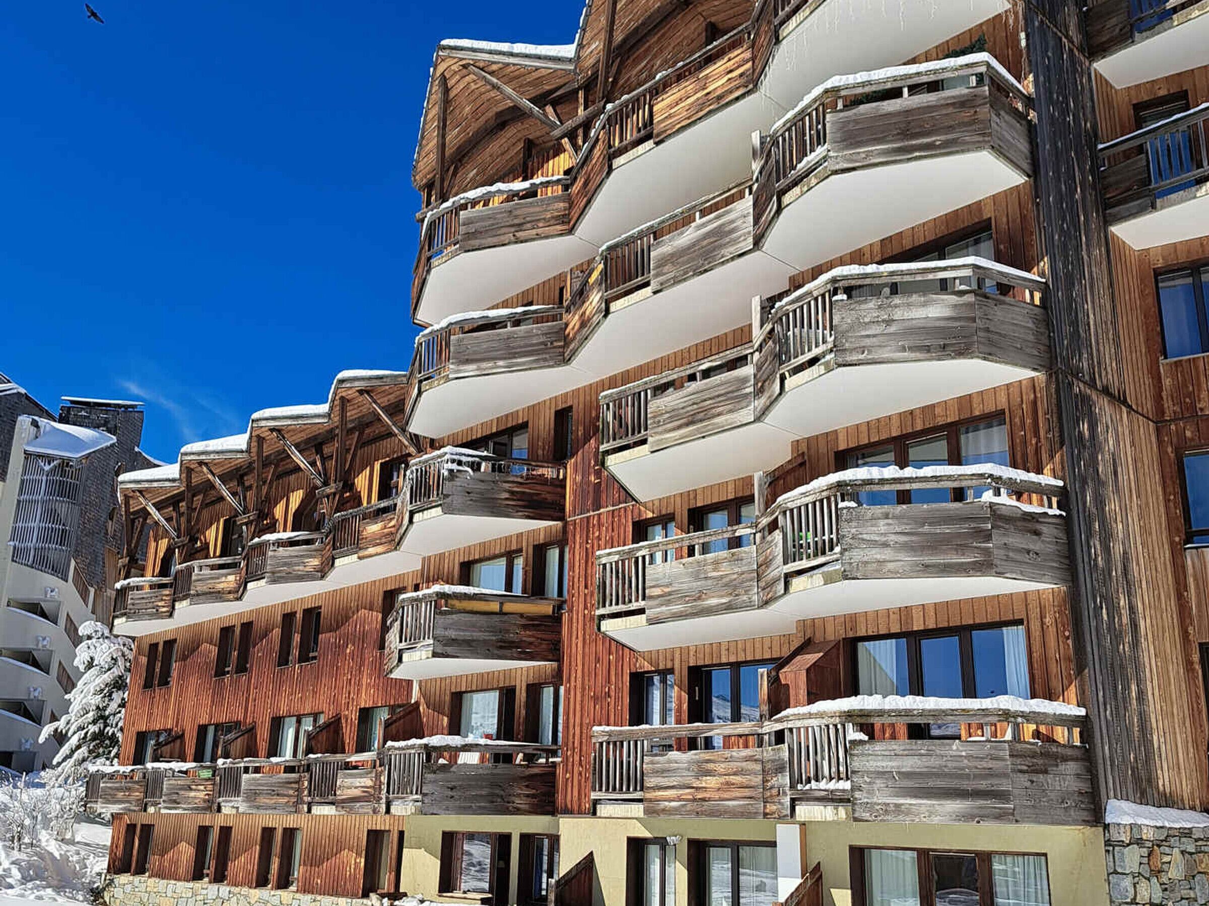 Un hôtel à plusieurs étages doté de balcons en bois et de grandes fenêtres.