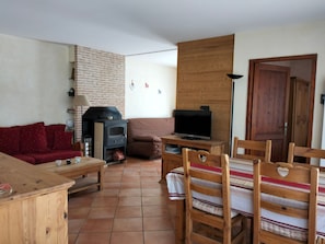 Cozy living room with a brick fireplace, television, and dining table.