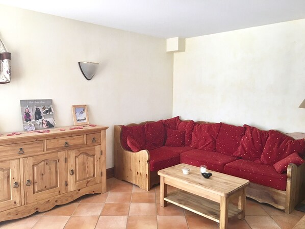 Un salon avec un meuble en bois, un canapé rouge et une table basse en bois.