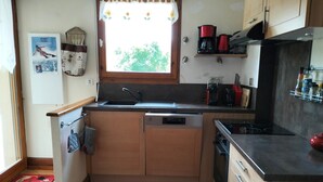 Una cocina compacta con ventana, un lavamanos, lavavajillas y estufa.