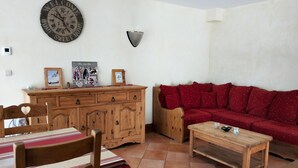 Una sala de estar con un aparador de madera, un sofá rojo, una mesa de centro de madera y un reloj de pared.