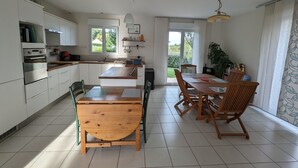 Eine moderne Küche mit weißen Schränken, einem Holztisch und einem großen Fenster.