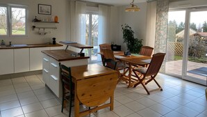 Eine moderne Küche mit Esstisch und Stühlen aus Holz, einem großen Fenster und Blick auf den Garten.