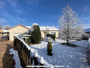 Une propriété résidentielle dotée d’un garage, d’une clôture en bois et d’arbres couverts de neige.