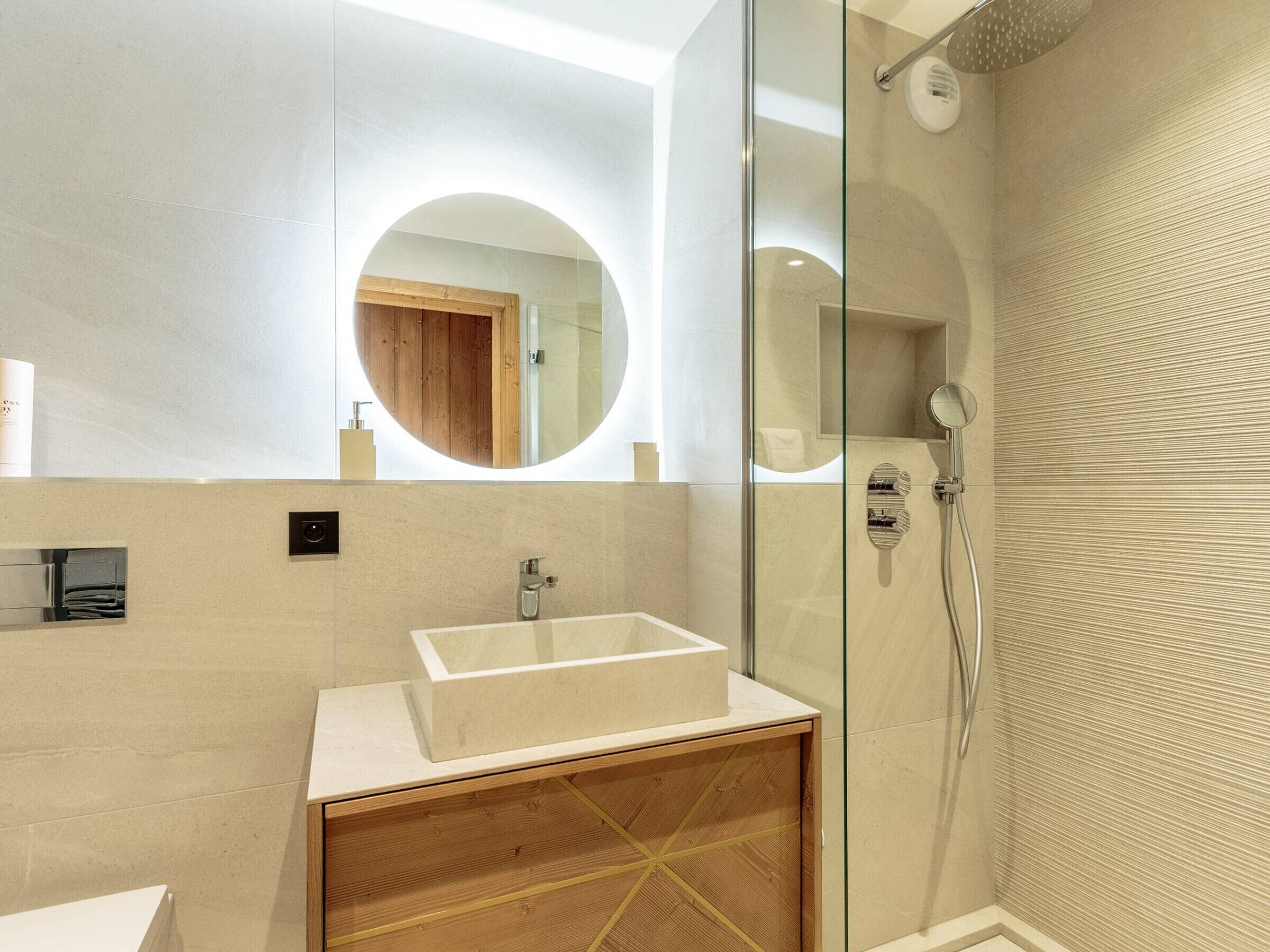 Un bagno moderno con cabina doccia in vetro, un mobile bagno in legno e uno specchio grande.