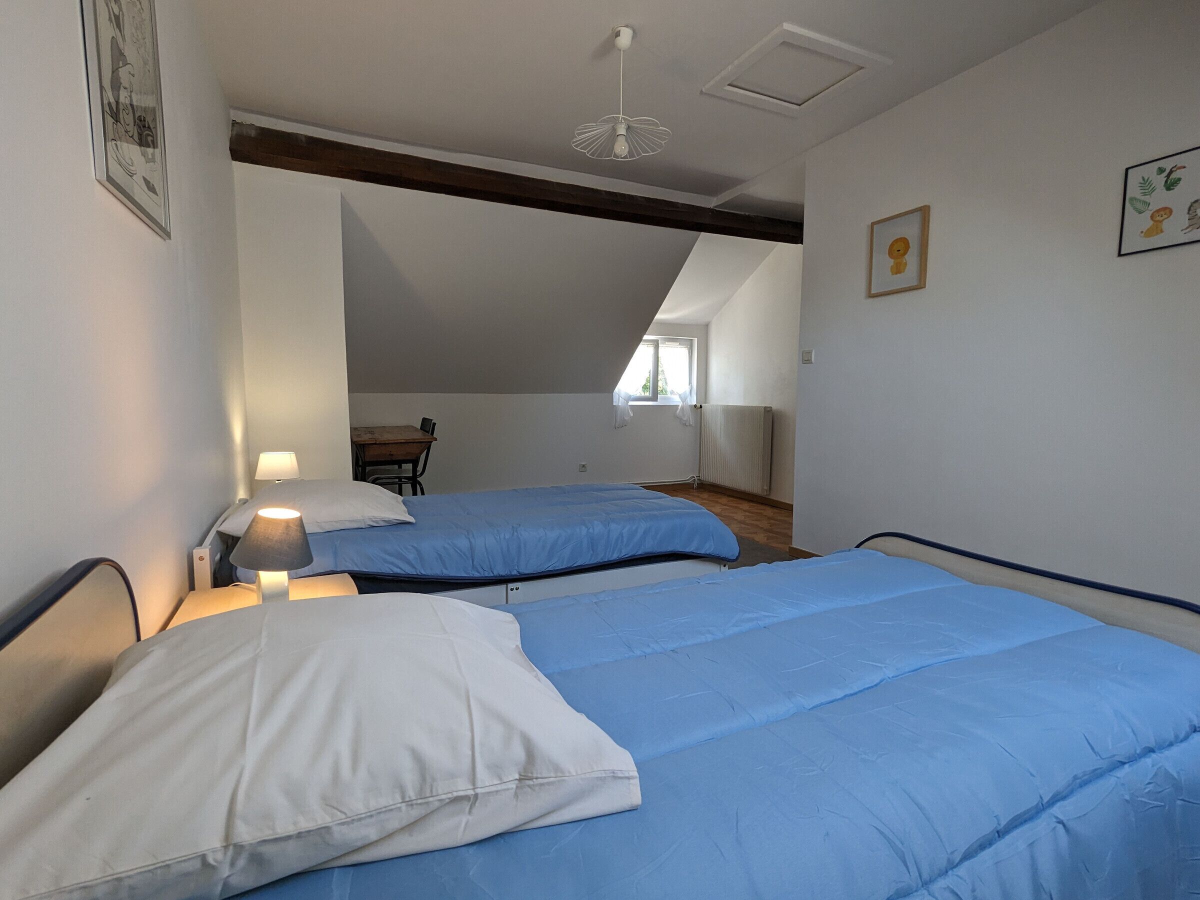 A bedroom with two beds, a desk, and a chair.