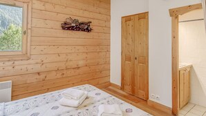 Ein Zimmer mit Holzwänden, einem Bett, einem Fenster und einer Tür.