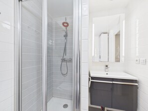 Ein Badezimmer mit einer Dusche in Glaswand, einem weißen Waschbecken und einem Spiegel darüber.
