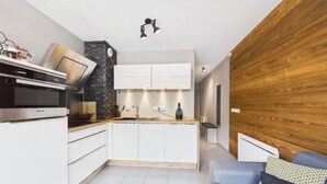 A modern kitchen with white cabinets, a built-in oven, and a stone accent wall.