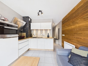A modern kitchen with white cabinets, a built-in oven, and a stone accent wall.