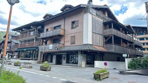 A multi-story building with balconies, a ground-level shop, and a sign for Nicolas Thibon Immobilier.