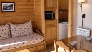 A wooden interior with a sofa, a dining table, and a kitchen area.