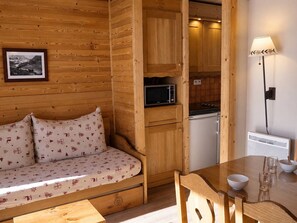 A wooden interior with a sofa, a dining table, and a kitchen area.