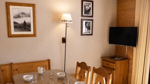 A dining area with a wooden table, chairs, and a television on a wooden cabinet.