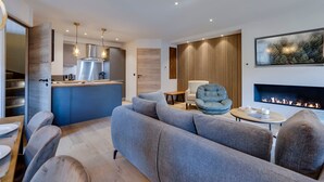 Ein modernes Wohnzimmer mit einem grauen Sofa, einem runden Couchtisch und einem Kamin.