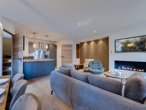 A modern living room with a grey sofa, a round coffee table, and a fireplace.