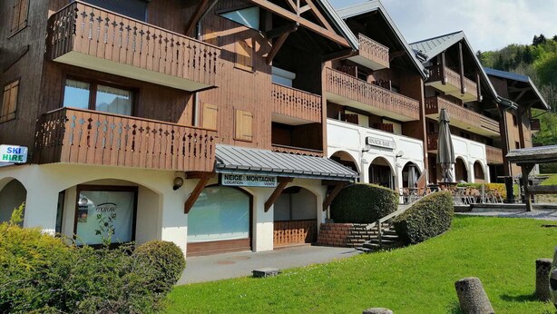 Ein Chalet-ähnliches Gebäude aus Holz mit Balkonen, einer Snackbar und einem Schild mit der Aufschrift ‚Skihaus‘.