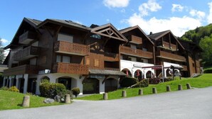 Ein traditionelles Chalet-Hotel mit mehreren Balkonen, einem überdachten Eingang und einer Seilbahn im Hintergrund.