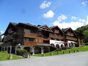 Un hotel in stile chalet tradizionale, con numerosi balconi, un ingresso coperto e una seggiovia sullo sfondo.