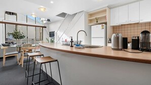 A modern kitchen with a wooden countertop, white cabinets, and a stainless steel kettle. - Prahran 3 Bed Escape - Prime Location (Prahran)