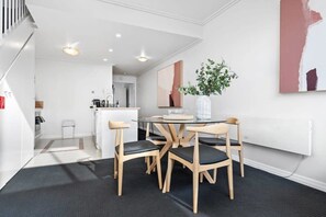 Eine moderne Küche mit Essbereich, ausgestattet mit einem runden Glastisch und Holzsesseln.