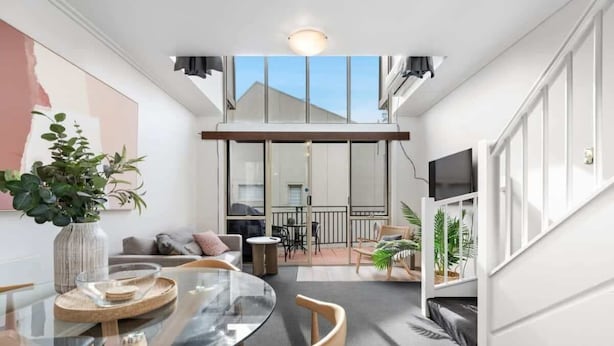 A modern interior with a glass dining table, wooden chairs, a sofa, and a TV mounted on the wall. - Prahran 3 Bed Escape - Prime Location (Prahran)
