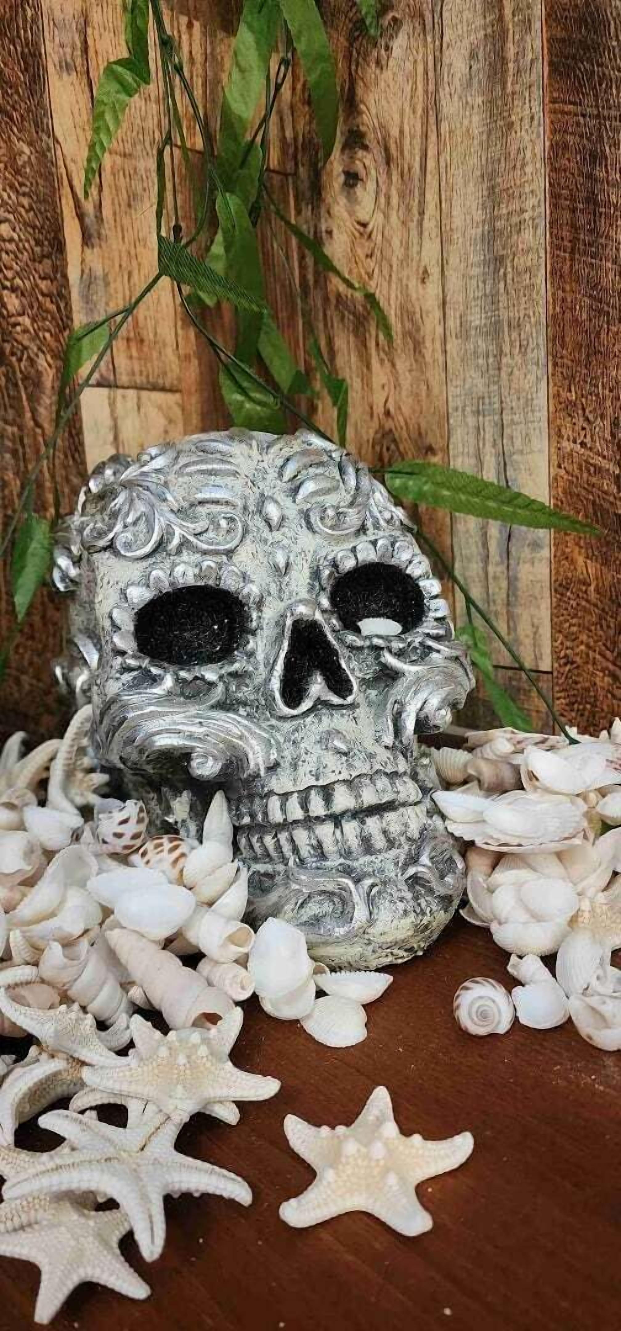 A skull sculpture surrounded by seashells and starfish on a wooden surface.