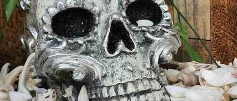A skull sculpture surrounded by seashells and starfish on a wooden surface.