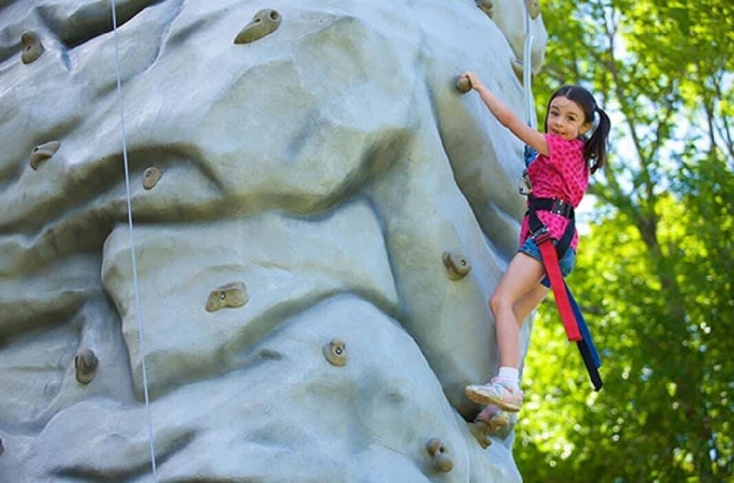 Un niño escalando una pared de escalada con agarres.