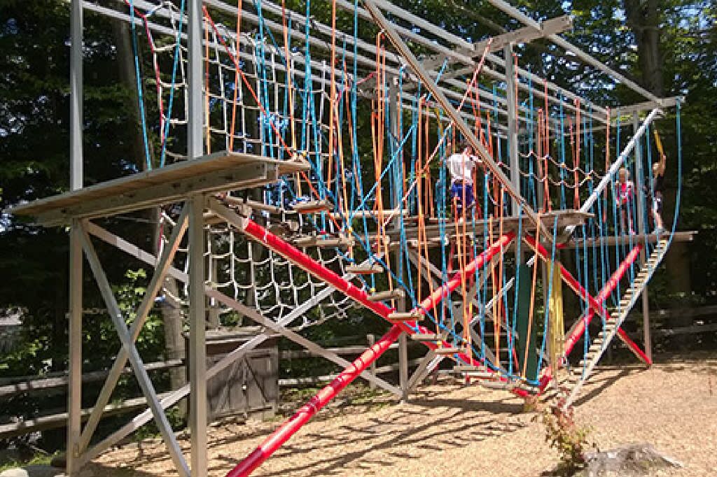Une structure de pont suspendu faite de cordes, avec plusieurs niveaux et des cordes de couleurs vives.
