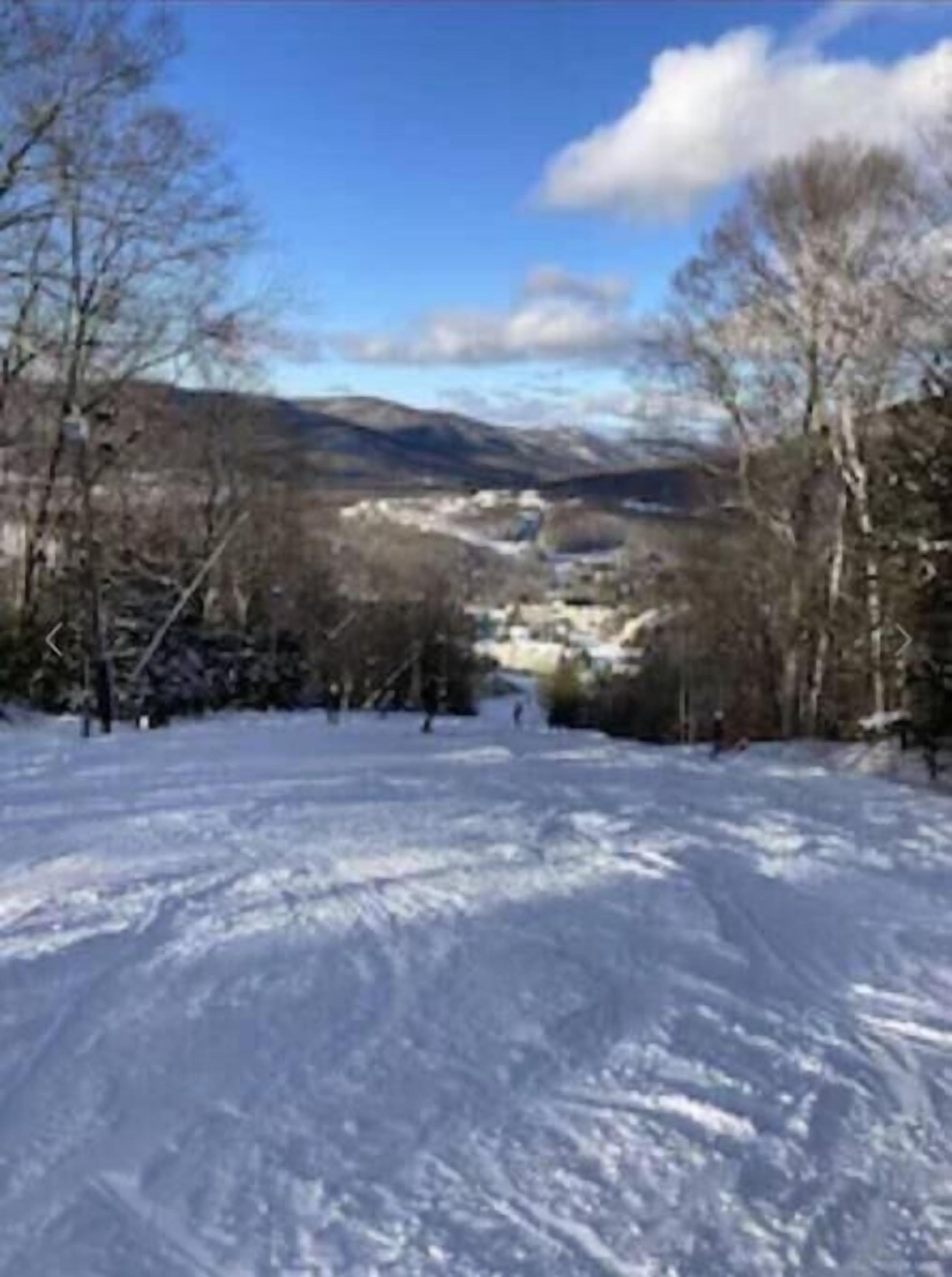 Schneebedeckte Landschaft mit blauem Himmel und fernen Bergen.