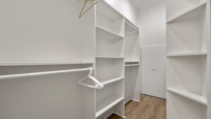 Ein begehbarer Kleiderschrank mit weißen Regaleinheiten und Holzboden.