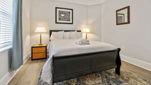 Ein ordentlich eingerichtetes Schlafzimmer mit einem Bett, zwei Nachttischen, einem Deckenventilator und Bildern an den Wänden.