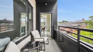 A balcony with a view of the city, a table, and two chairs. - Highline Hideaway | Corner 1BR LoHi Loft | Quiet | Dog-Friendly (Denver)