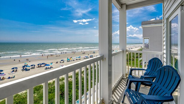 Ein Balkon mit Blick auf Strand und Meer.
