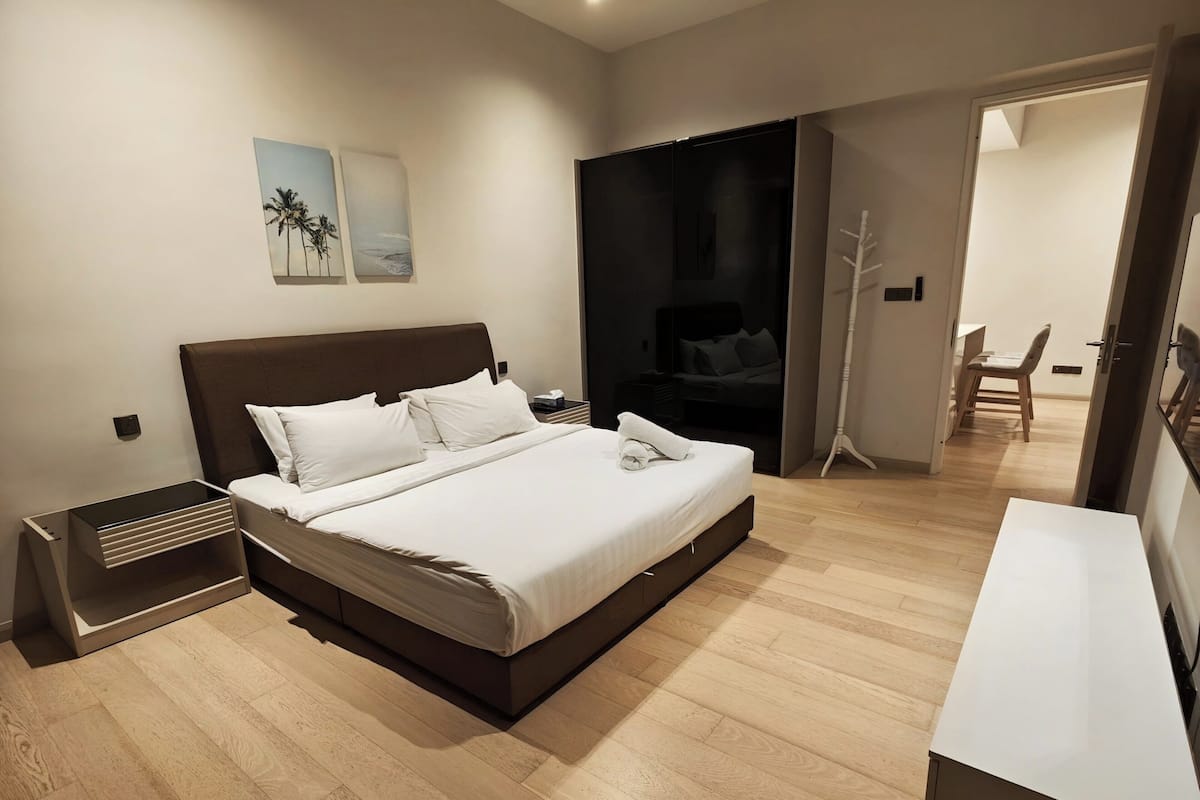 A modern bedroom with a large bed, bedside tables, a desk, and a chair.
