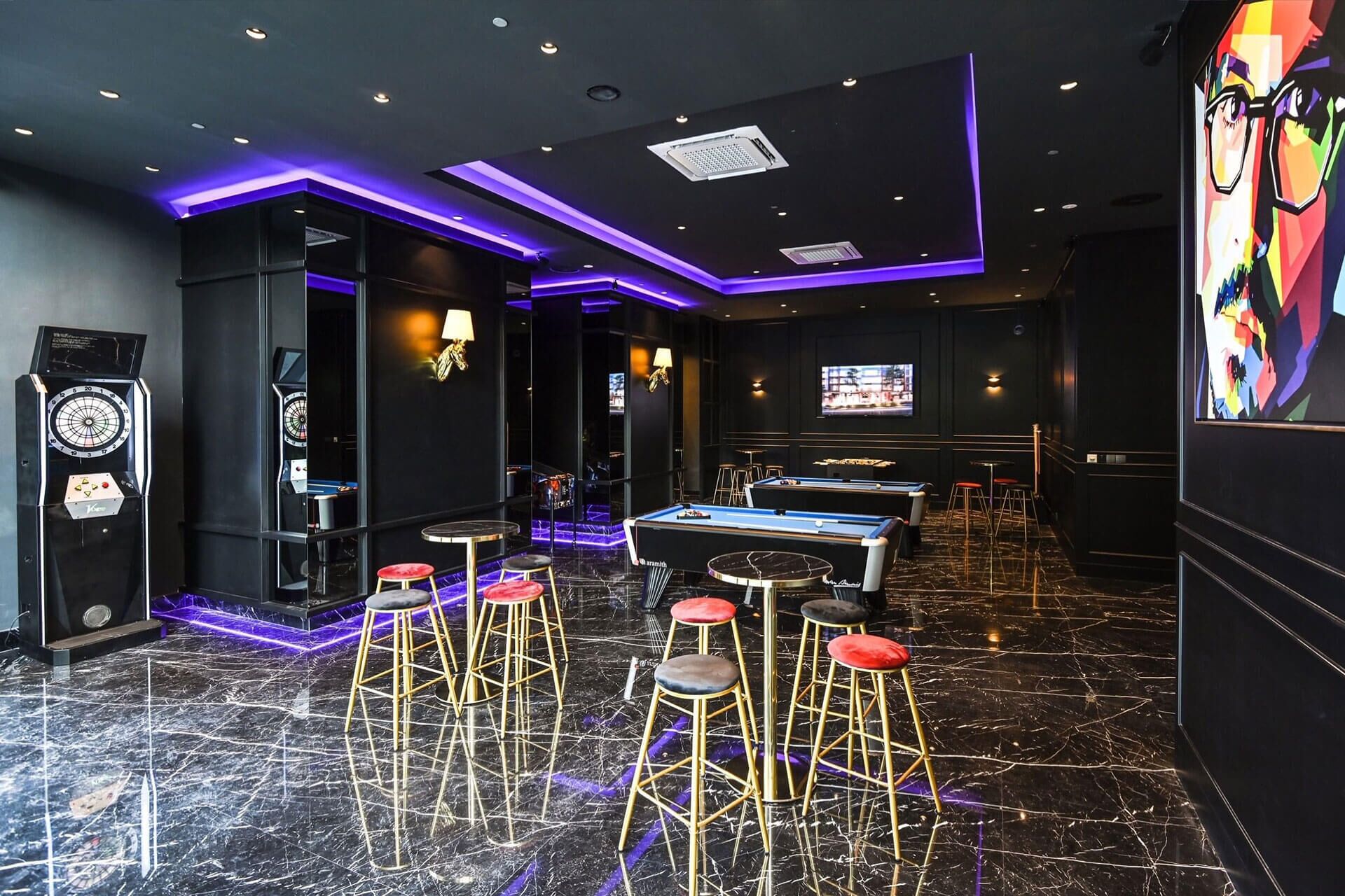 A billiards room with a pool table, stools, and a dartboard.