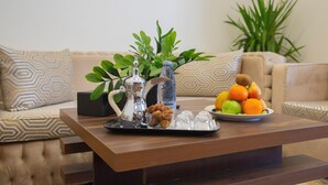 A wooden coffee table with a tray of snacks and a plate of fruit. - Vandal Hotels (Jizan)