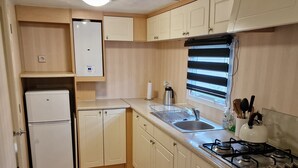 Eine kleine Küche mit Kühlschrank, Spüle, Herd und Holzboden.