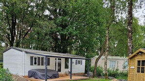 Ein Wohnmobil mit überdachter Terrasse und einem eingezäunten Garten.