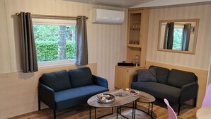 Un espai habitable reduït amb dos sofàs, una taula petita i una cadira rosa.