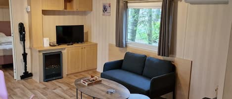 Un espacio habitable pequeño con sofá, una mesita, televisor y chimenea.