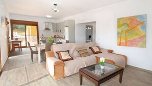 A modern living room with a sofa, a glass coffee table, and a dining area with chairs and a table.