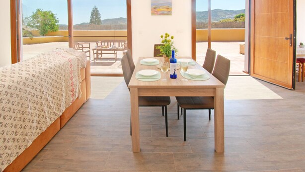 A dining area with a table set for four, a sofa, and a view of the outdoors.