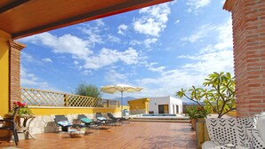 A patio with sun loungers, a tiled floor, and a view of the sky.