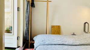Een slaapkamer met een bed, een houten hoofdeinde, een raam met gordijnen en een deur.