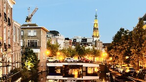 Een gracht met gebouwen aan weerszijden, een brug en een toren in de verte.