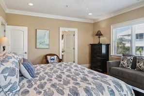 A bedroom with a bed, a dresser, a couch, and a window.